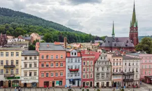 Kolorowe kamienice i kościół z zieloną wieżą tworzą malowniczy widok. Odkryj **Nowa Ruda atrakcje** i poczuj klimat tego miejsca.