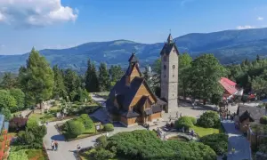 Drewniany kościółek i wieża na tle górskich krajobrazów. Czy to Karpacz, czy Szklarska Poręba?