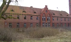 Opuszczony budynek z cegły, zniszczony dach i wybite okna. Miejsce to mogłoby być jednym z nawiedzonych miejsc w Polsce, budzącym grozę.