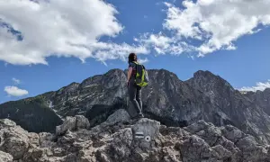 Widok z Sarniej Góry na skaliste szczyty i lasy. Turystka z plecakiem podziwia panoramę.