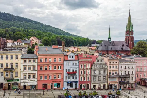 Kolorowe kamienice i kościół z zieloną wieżą tworzą malowniczy widok. Odkryj **Nowa Ruda atrakcje** i poczuj klimat tego miejsca.