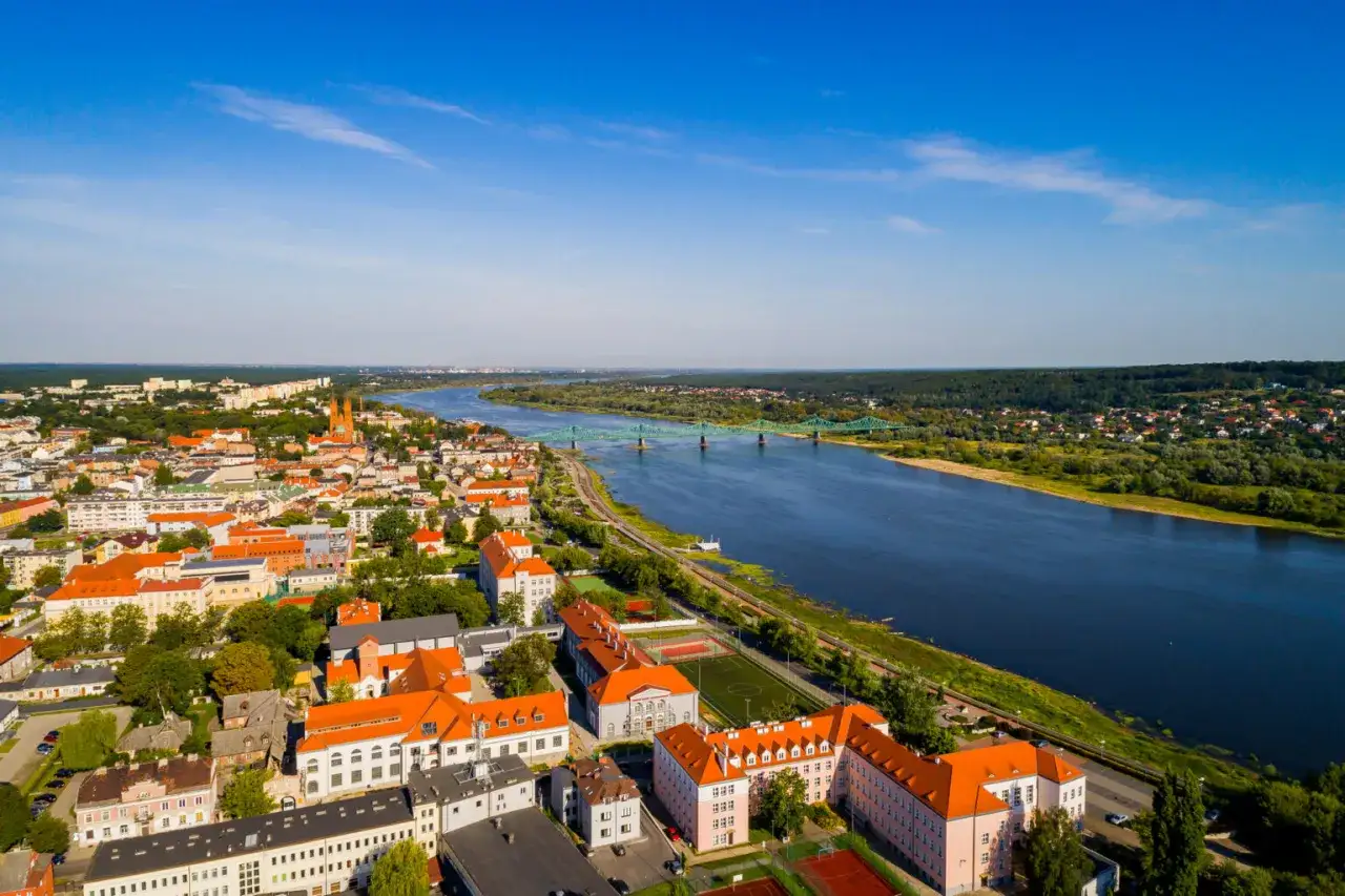 Widok z lotu ptaka na zabytkowe miasto nad Wisłą, z charakterystyczną architekturą i zielonym mostem.