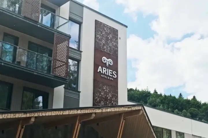 Nowoczesny hotel Aries w Szczyrku z ozdobnymi panelami i widokiem na las.